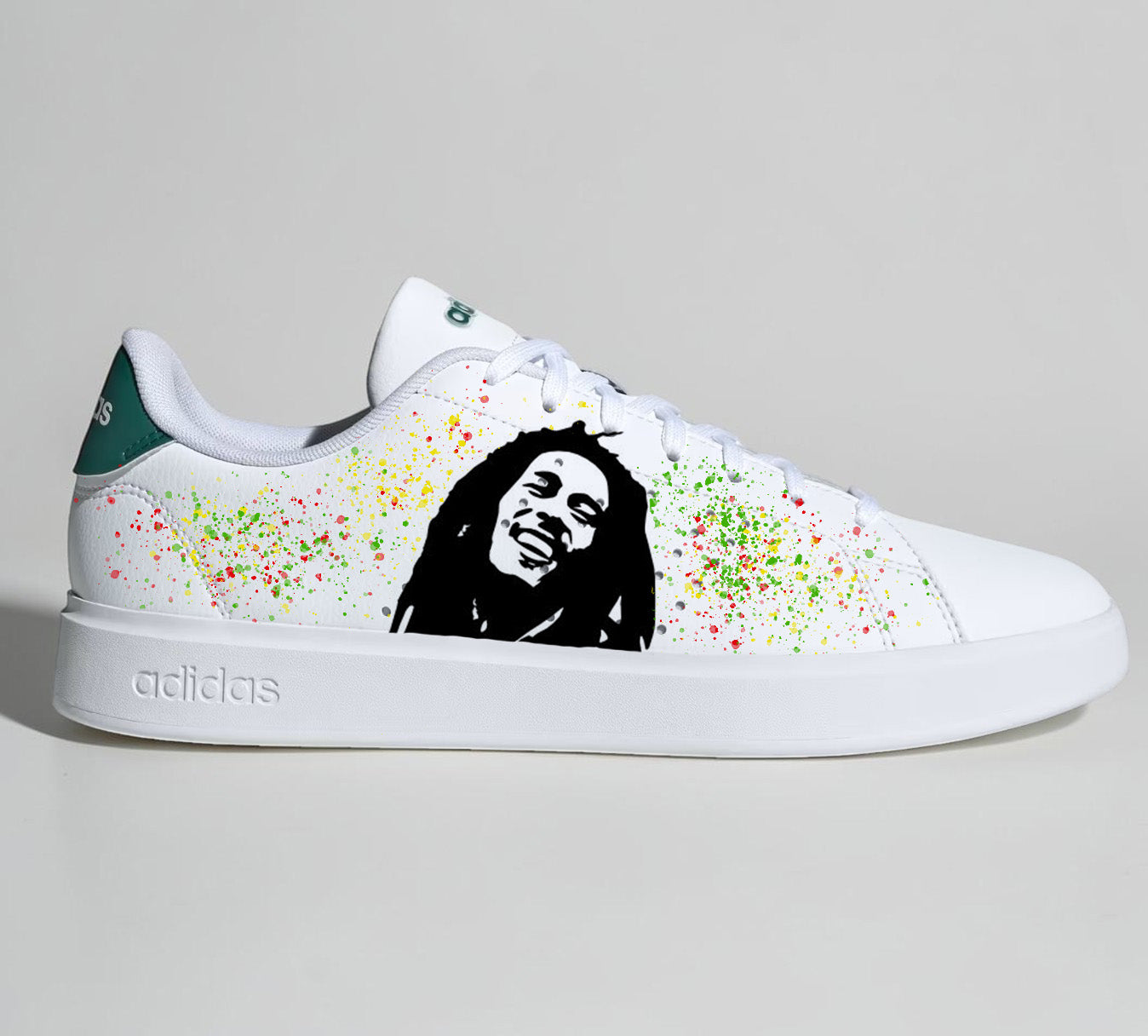 Baskets Adidas blanches personnalisées avec portrait de Bob Marley et éclaboussures de peinture rasta.